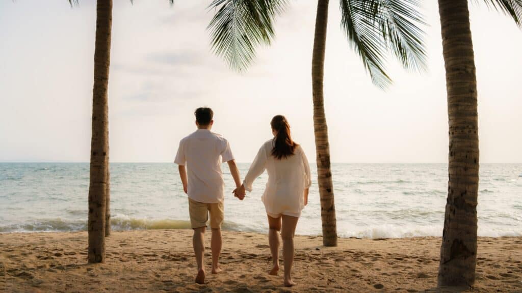 The Hidden Downside To Booking the Cheapest All-Inclusive Deals 7 Asian couple is running and holding hands on a beach