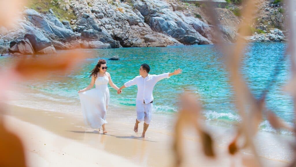 Cruise vs All-Inclusive Resort for Honeymoon Bliss: A Guide 3 Couple walking on sandy beach near ocean