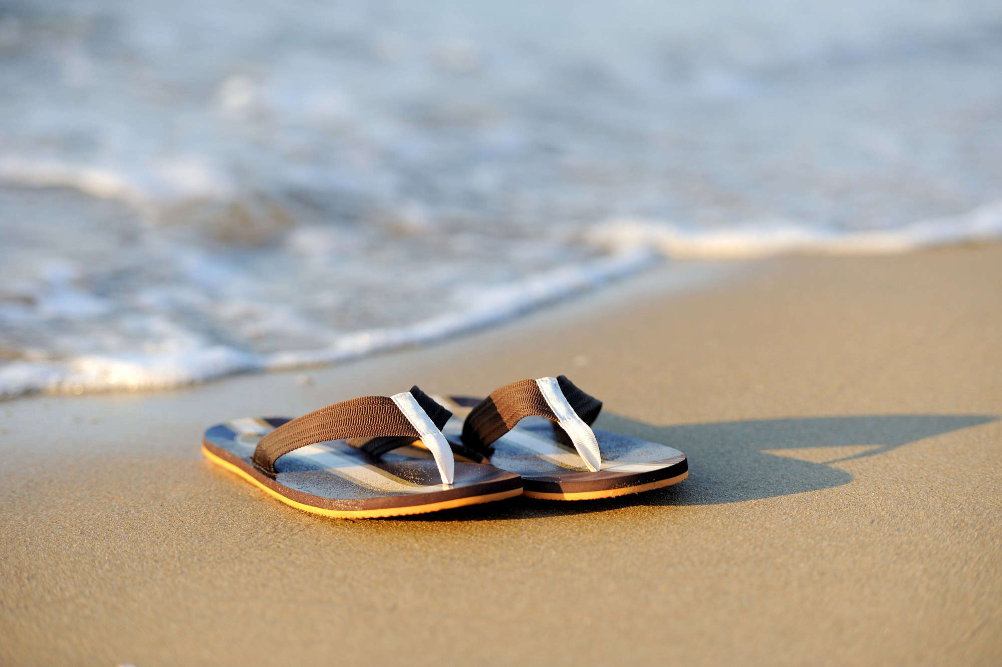 Master Packing for Paradise With These 15 Tips 9 Flip flops on a sandy ocean beach
