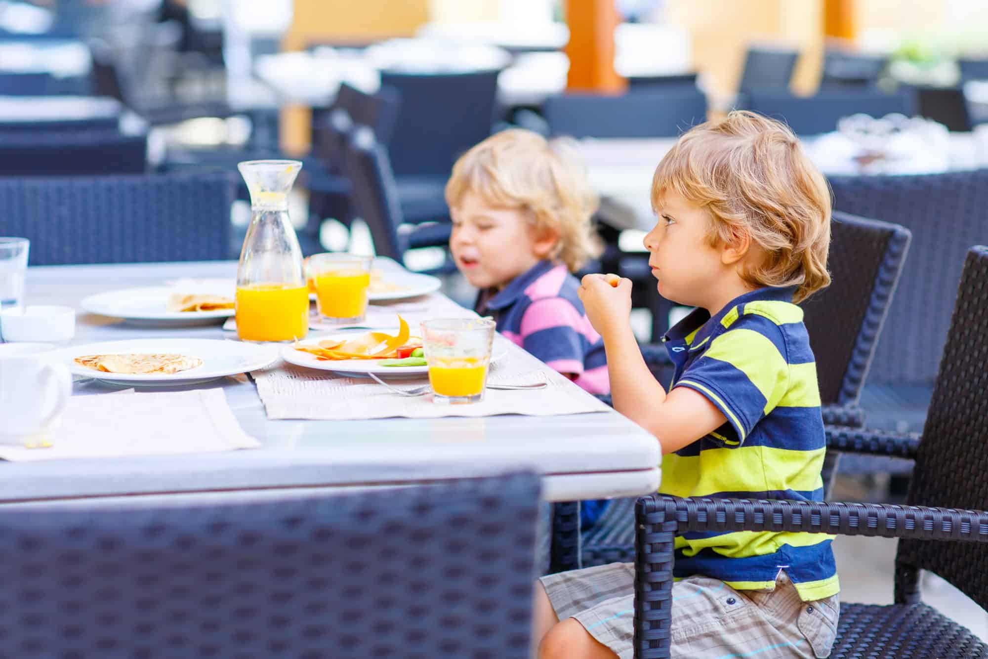 Two kid boys having a healthy breakfast at a hotel