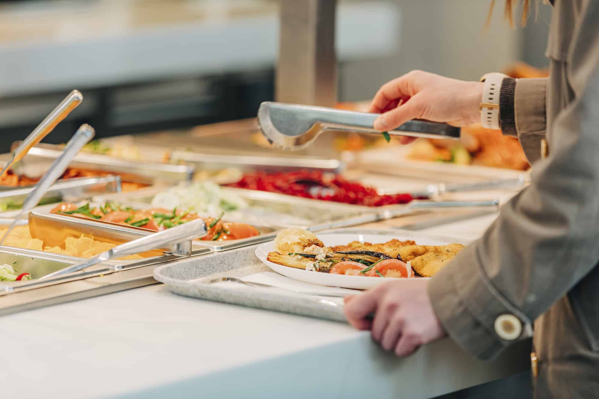 7 All-Inclusive Dining Mistakes Everyone Makes (And How To Avoid Them) 2 Woman puts food on her plate at the buffet
