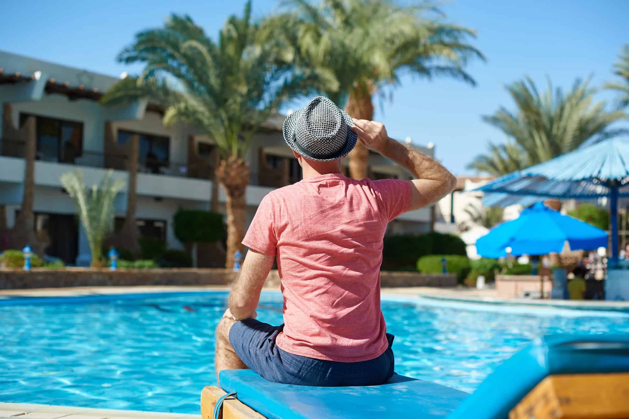Master Packing for Paradise With These 15 Tips 4 Young Man in Hat Sitting On Sun Lounger
