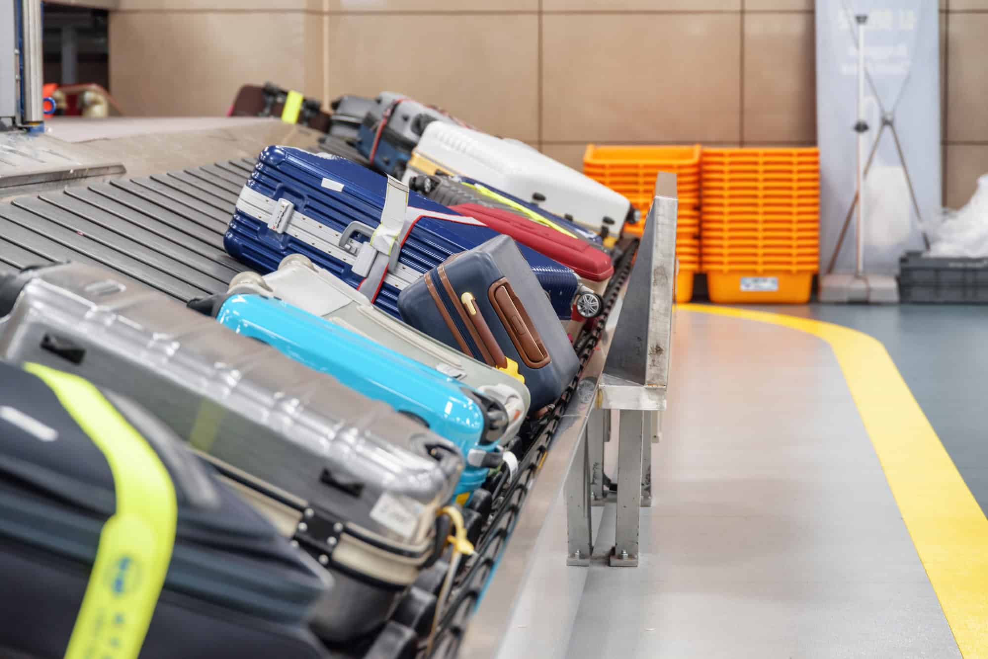 The Genius Trick to Keep Your Luggage From Getting Lost at the Resort 6 Suitcases on luggage conveyor belt in airport