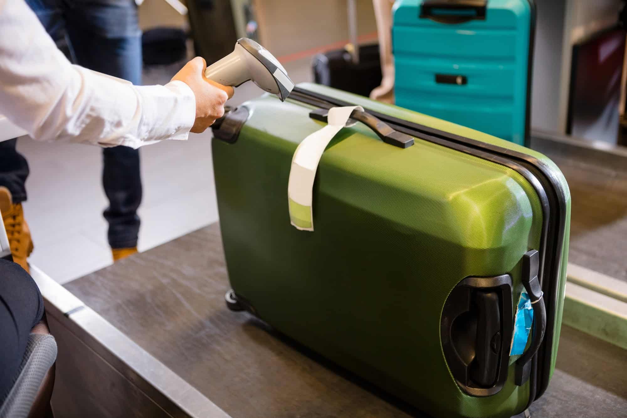 The Genius Trick to Keep Your Luggage From Getting Lost at the Resort 2 Woman Scanning Tag On Luggage At Airport Check-in