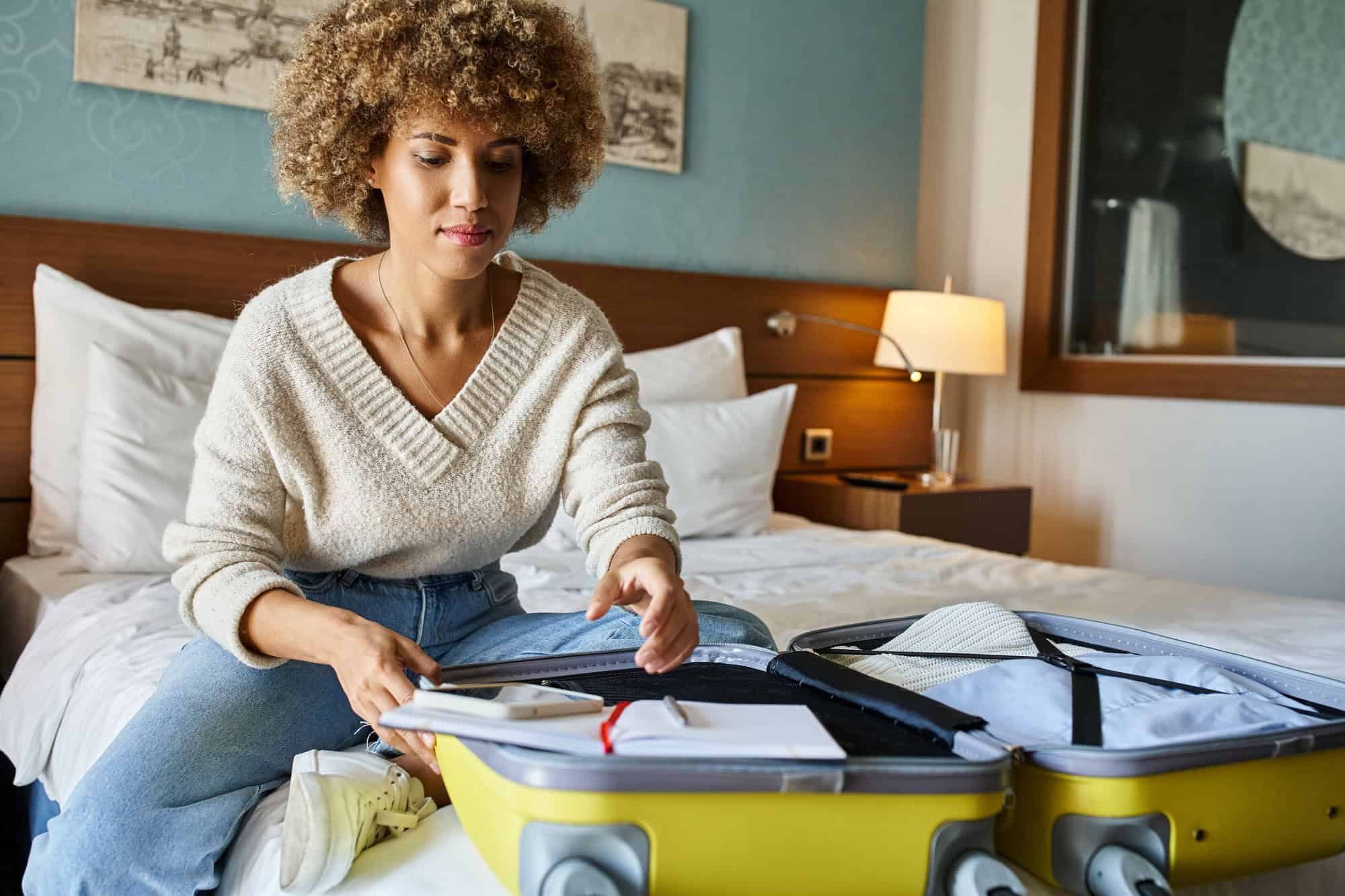 The Genius Trick to Keep Your Luggage From Getting Lost at the Resort 5 Young woman unpacking suitcase